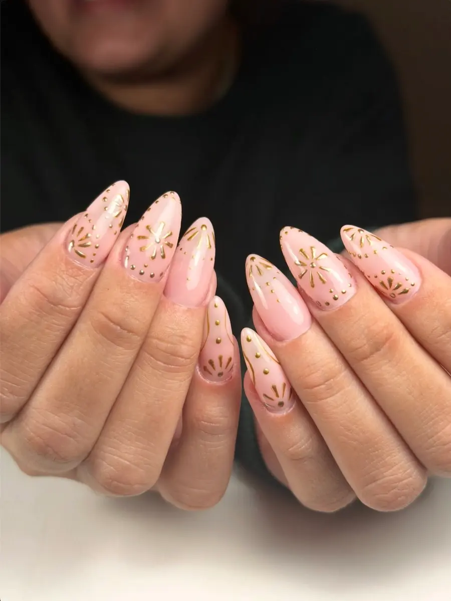 Uñas rosa con dibujos dorados hechos a mano